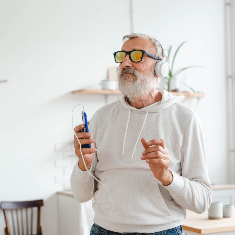 Happy senior man dancing while listening to music with headphones - active old people and enjoyment mood